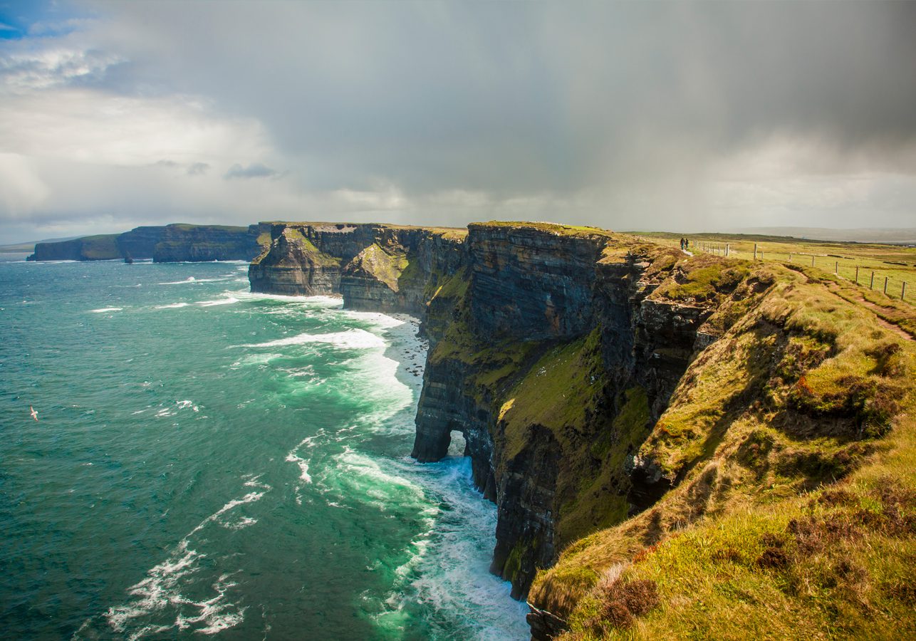 A view of the rugged cliffs of Moher on the west coast of Ireland with a stormy sky and crashing waves