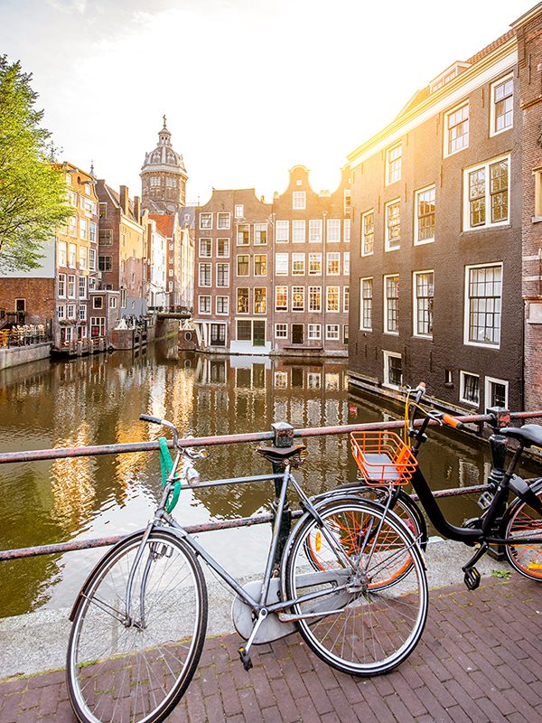 View of a canal in Amsterdam with histroric buildings lining the canal and bikes in the foreground